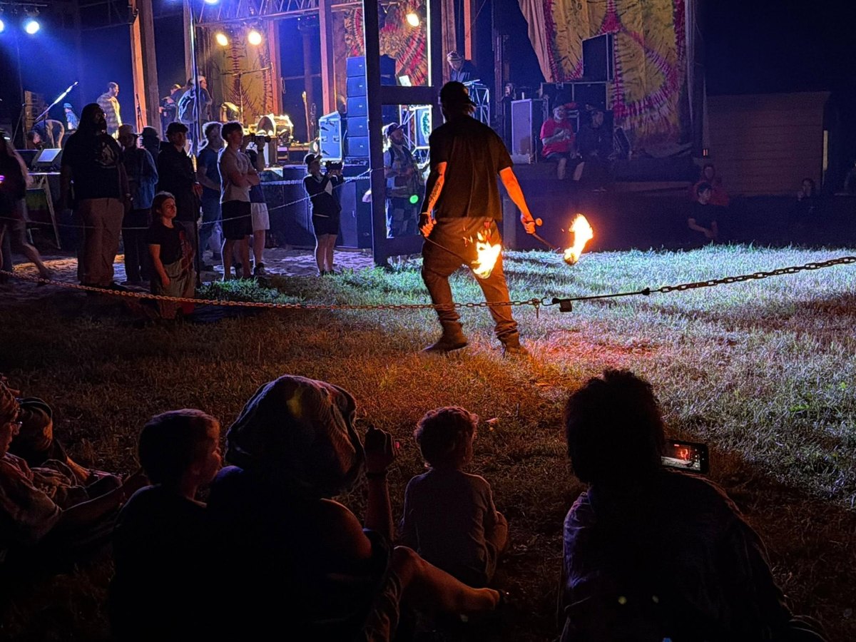 Fire spinner performing at night for the crowd at Infinite Cypher in Tionesta, PA